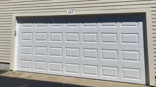 Insulated white raised-panel double garage door on a Cape Cod home