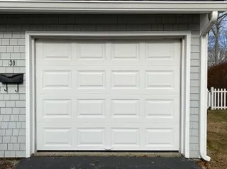 Insulated white single garage door on a shingled Cape Cod home